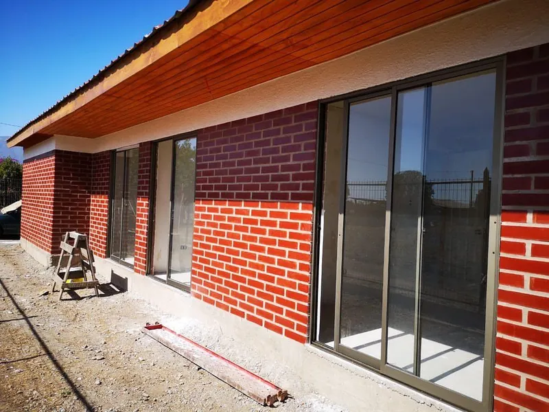 Casa en obra con grandes ventanales, en etapa de construcción